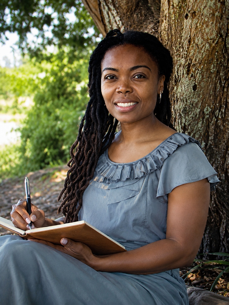 Latoya Bridgewater writing in her journal under a tree in Caribbean